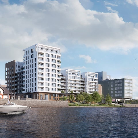 Moderní bytové domy u řeky za slunečného dne s lodí